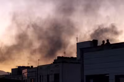 People stand on a rooftop amidst billowing smoke following an overinght Israeli strike in Tehran on June 17, 2025. (Photo by ATTA KENARE / AFP)
