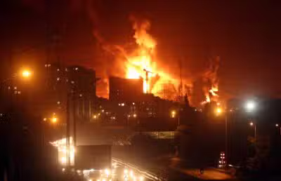 TEHRAN (IRAN(Islamic Republic Of)), 15/06/2025.- People drive as fire and smoke rise from Tehrans oil warehouse in Tehran, Iran, 15 June 2024. Israel continues strikes on Irans nuclear program and energy facilities. (Teherán) EFE/EPA/ABEDIN TAHERKENAREH