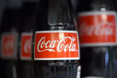 (FILES) In this file photo taken on February 10, 2022 bottles of Coca Cola products are displayed in a cooler at Colonial Liquors in Corte Madera, California. - Coca-Cola, under pressure from environmentalists over its packaging policies, has pledged to use reusable containers for at least 25 percent of its beverages by 2030. (Photo by JUSTIN SULLIVAN / GETTY IMAGES NORTH AMERICA / AFP)