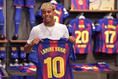 Barcelona's Spanish forward Lamine Yamal poses holding his new #10 jersey at the Camp Nou stadium's shop on July 16, 2025 in Barcelona. Young Barcelona star Lamine Yamal inherited the club's number 10 shirt, previously worn by all-time great Lionel Messi, today. The 18-year-old winger, often compared to the Argentine superstar who also came through the club's La Masia youth academy, helped the Catalan giants win a domestic treble last season. (Photo by MANAURE QUINTERO / AFP)